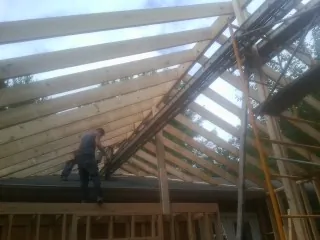 Rafters going up over a new addition with a worker on the wall in Jordan
